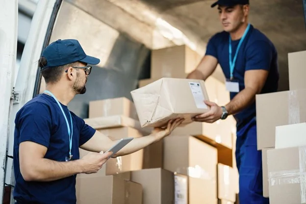 2 men passing boxes out from the back of a delivery van