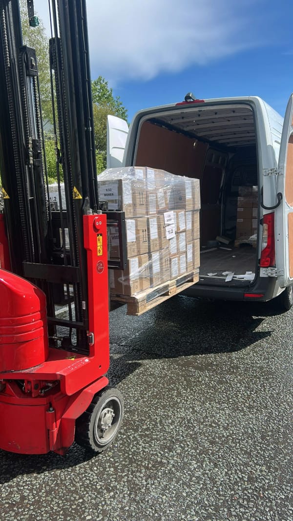 Red forklift loading a white van