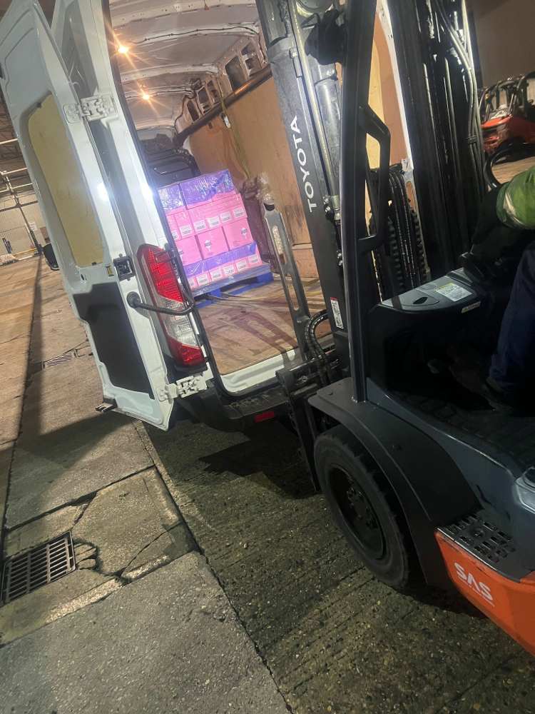 Large van being loaded by a forklift carrying heavy boxes