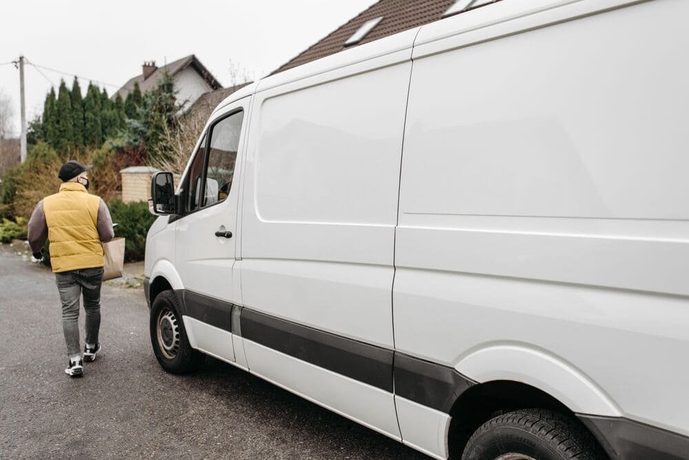 White van with courier driver leaving it